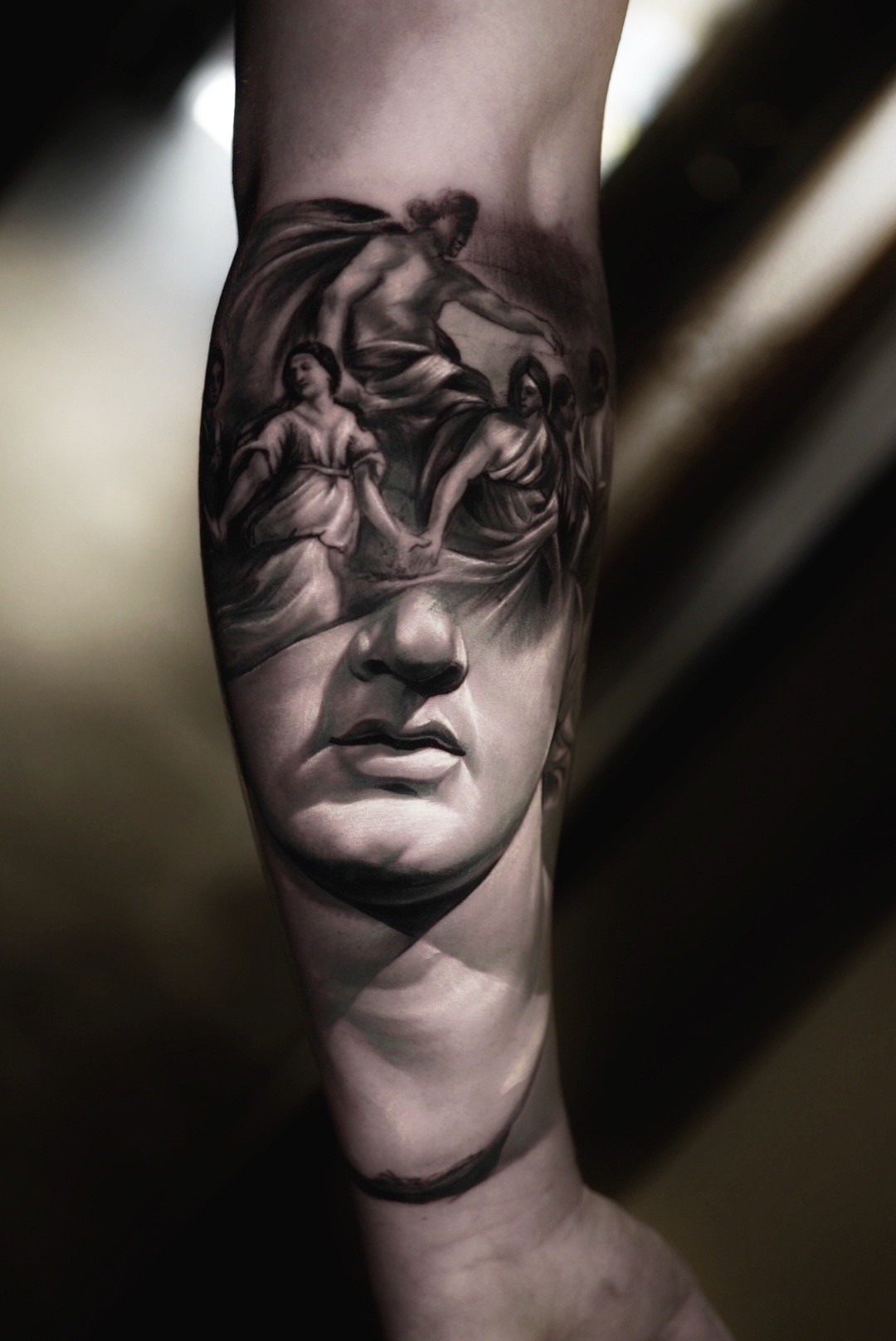 Realistic black and grey tattoo of a classical statue on a forearm